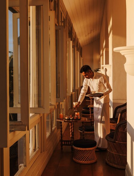 Sunset light filters through wooden shutters onto a corridor at Amangalla, casting warm shadows along the passage.