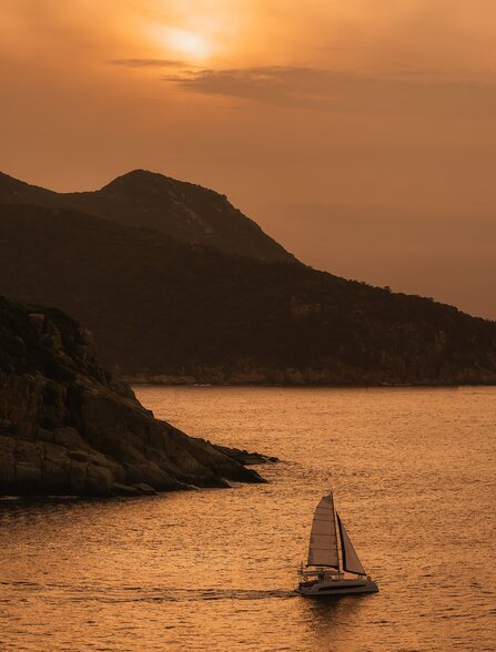 Catamaran sailing at sunset off the coast near Amanoi, Vietnam.