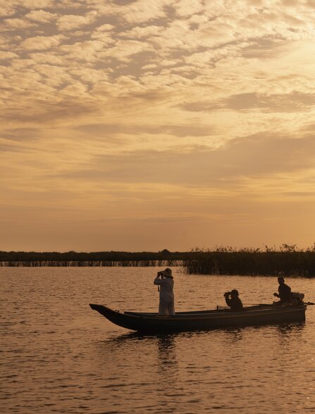 Fisherman in wooden boat at sunset on Tonlé Sap Lake, Amansara.