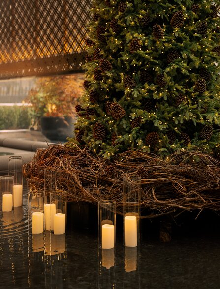Candlelit courtyard at Aman New York with ivy-covered walls and reflective water feature at dusk.