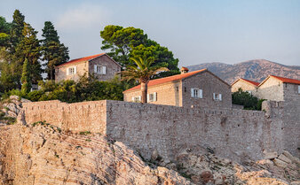 Sveti Stefan Suite at Aman Sveti Stefan, Montenegro: terracotta-roofed buildings perched on a rocky islet at dusk.