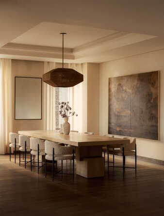 Dining room at Aman New York with wooden table, pendant light, and neutral-toned walls.