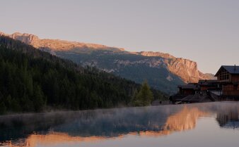 Outdoor pool at Aman Rosa Alpina overlooking alpine mountains at sunrise, Italy.