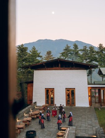 Amankora cultural programme in Thimphu, with guests gathered in a courtyard beneath mountain views.