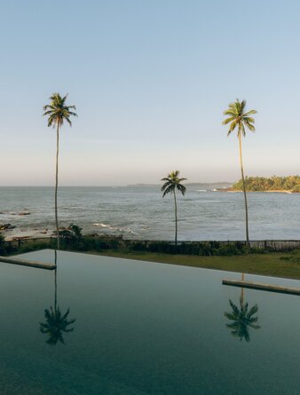 Infinity pool overlooking the Indian Ocean at Amanwella, Sri Lanka, with palm trees reflected in still water.