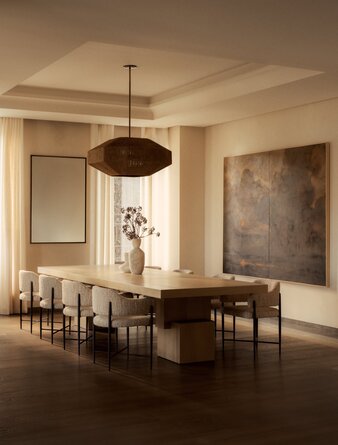 Three-bedroom penthouse dining room at Aman New York with wooden table, pendant light, and gallery walls.