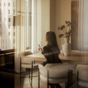 Penthouse PH24 three-bedroom home in New York with guest seated at desk by tall windows.