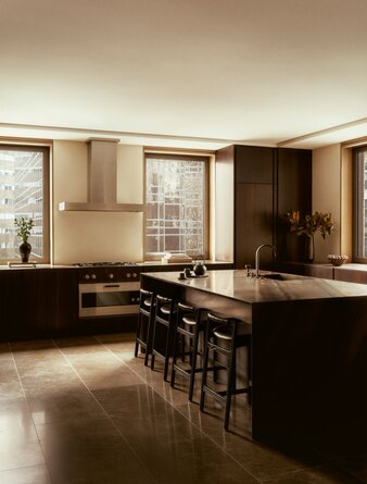 Penthouse kitchen with dark cabinetry, wooden accents, and bar seating at Aman New York.