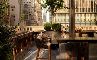Garden terrace at Aman New York with seating overlooking the city skyline.