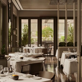 Arva dining venue at Aman New York, with table settings overlooking verdant city views through tall windows.