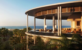 Casa Grande Lodge at Aman Mexico with curved wooden architecture overlooking mountain landscape at dusk.