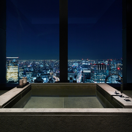 Soaking tub overlooking Tokyo's illuminated cityscape at night from Aman Tokyo.