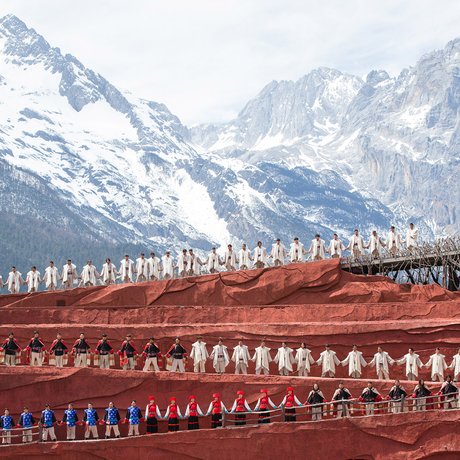 Amandayan's courtyard with snow-capped mountains and traditional red-roofed buildings with ornamental details.