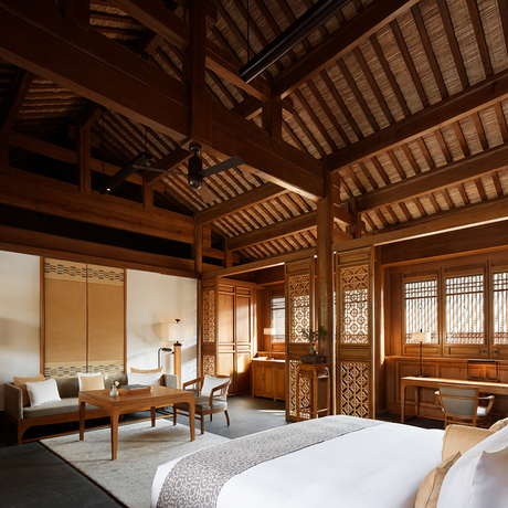 Principal bedroom at Amandayan with wooden ceiling beams, traditional furnishings, and large windows overlooking the landscape.