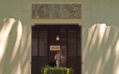Amanfayun entrance with dark wooden doors framed by white walls and traditional artwork above.