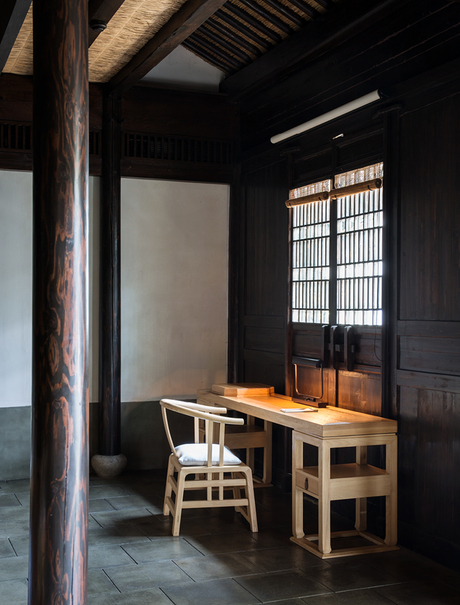 Simple wooden desk and chair beside a latticed window at Amanfayun.