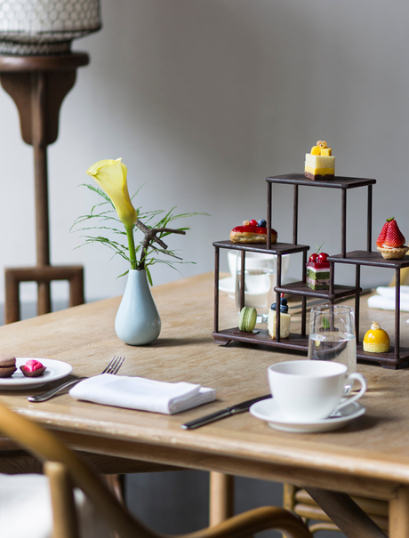 Wooden desk at Amanfayun with yellow flowers, open notebook, and decorative shelving unit.
