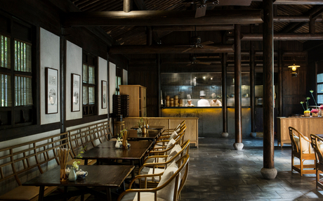 Amanfayun's dining venue with wooden tables and chairs, framed artworks on walls, and warm overhead lighting.