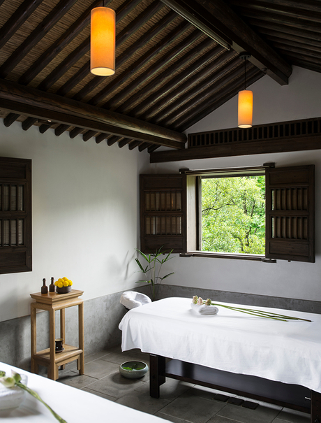 Amanfayun spa treatment room with striped wooden ceiling, pendant lights, and bathtub overlooking garden views.