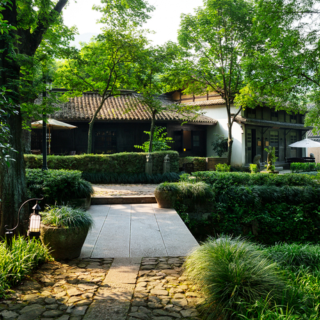 Courtyard at Amanfayun with manicured hedges and traditional architecture framed by mature trees.