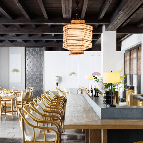 Dining area at Amanfayun with wooden chairs, long table, and pendant lighting beneath exposed beams.