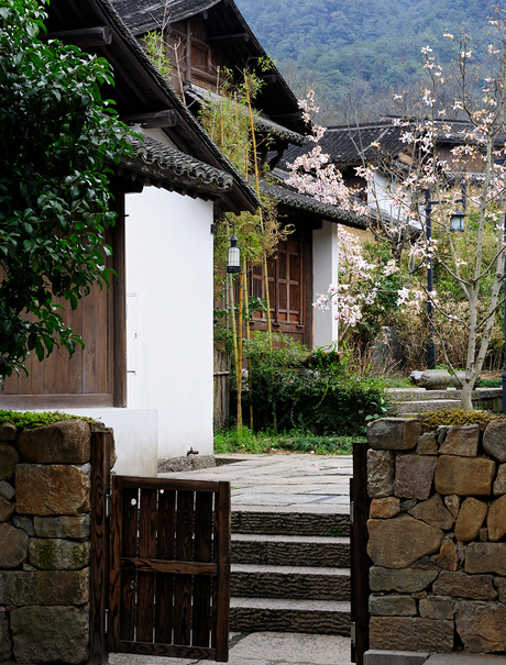 Stone gateway with wooden door leading to Amanfayun courtyard, ivy-clad walls beyond.