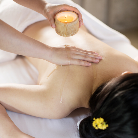 Therapist applying golden massage oil to guest's back at Amanfayun.