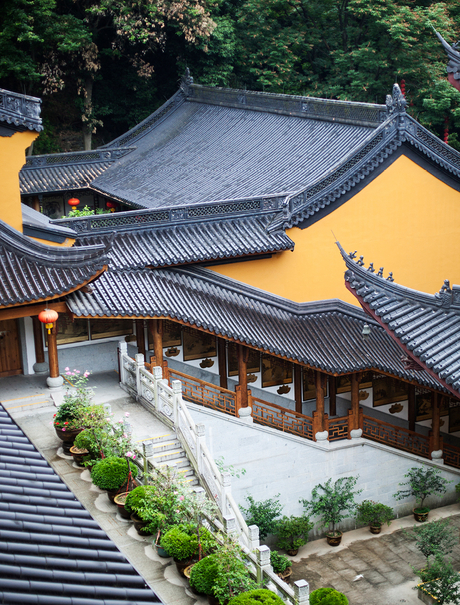 Amanfayun's traditional curved rooflines with yellow walls and manicured gardens nestled among green hillside vegetation.