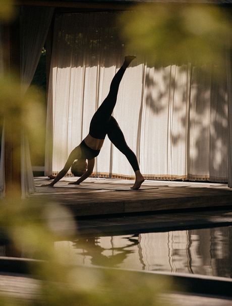 Guest practising yoga in a light-filled studio at Amanyara, reflected in still water below.