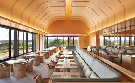 Dining venue at Amanemu resort with wooden barrel-vaulted ceiling and expansive windows overlooking the coastline.