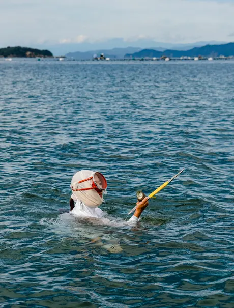 Guest swimming in calm coastal waters at Amanemu resort.
