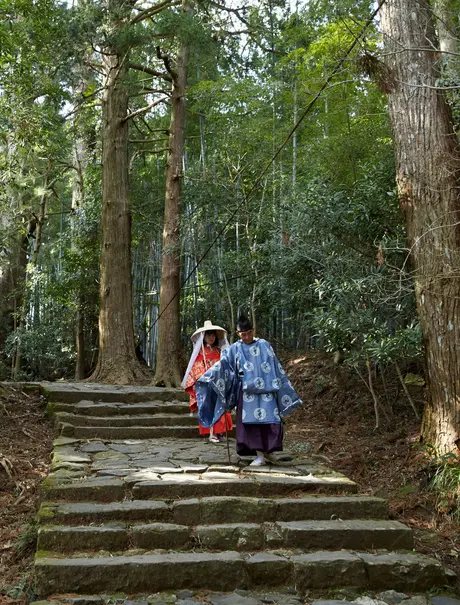 Two guests walking along stone steps through a forested pathway at Amanemu resort.