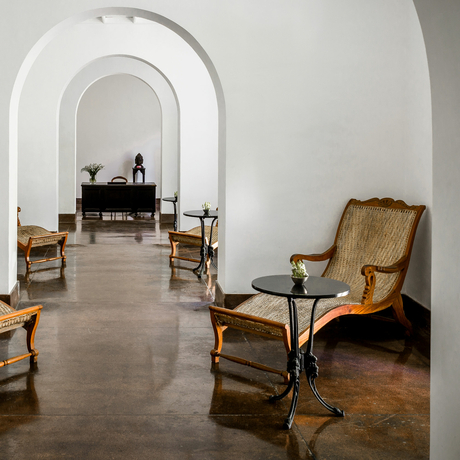 Arched corridor at Amangalla with period furniture and whitewashed walls.