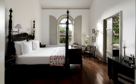 Principal bedroom at Amangalla with four-poster bed and arched doorways opening to gardens.
