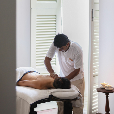 Therapist administers a massage treatment to a guest at Amangalla.