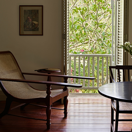 Wooden chairs beside a window with garden views at Amangalla, Sri Lanka.