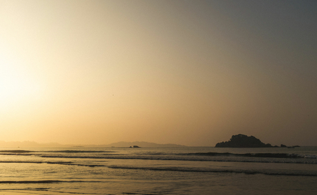 Sunrise over calm waters at Amangalla, with a distant island silhouetted against the golden sky.