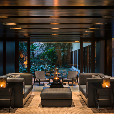 Amansara's open-sided pavilion with seating areas and garden views at dusk.