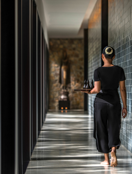 Woman in black dress walking through colonnade at Amansara.