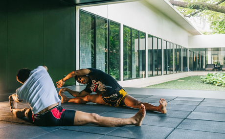 Yoga mat and props arranged on a stone terrace at Amansara, with green walls and glass doors beyond.