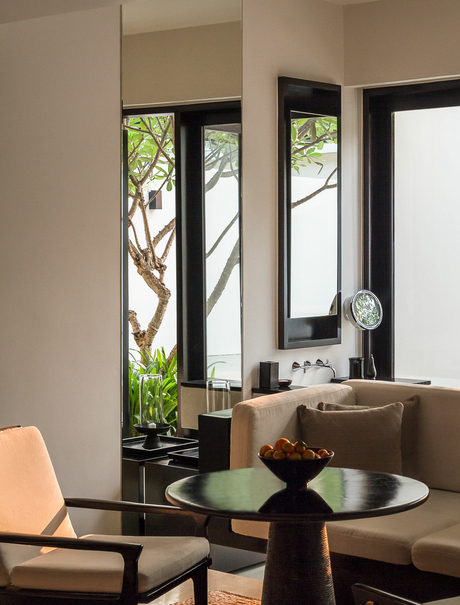 Workspace at Amansara with desk, chair, and tall mirror reflecting garden views through windows.