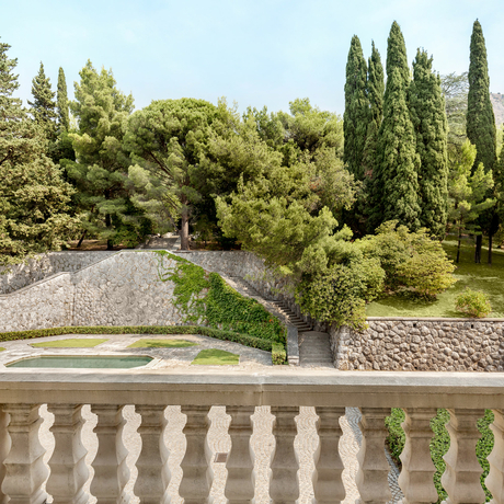 Stone balustrade overlooking manicured gardens with cypress trees at Aman Sveti Stefan, Montenegro.