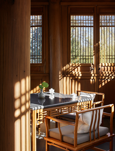 Sunlit dining area at Amandayan with wooden screens casting geometric shadows across a table set for two.