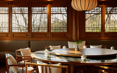 Circular dining table with chairs in a wood-panelled room at Amandayan, with latticed windows and hanging lantern.