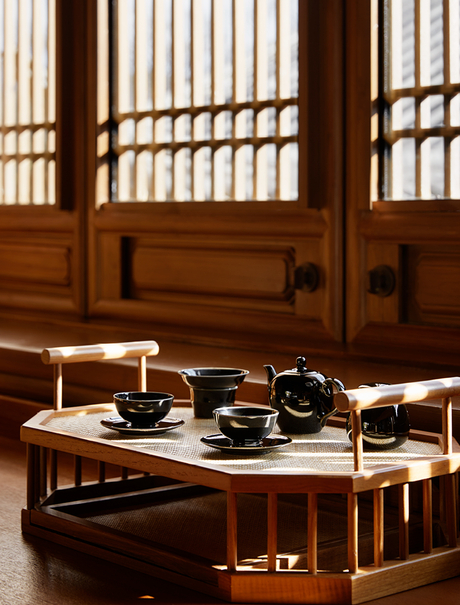Traditional tea service set on low wooden table at Amandayan, with vertical latticed screens casting striped shadows in background.