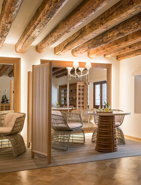 Sunlit gallery space at Aman Venice with exposed wooden beams, elegant furniture, and classical architectural details.