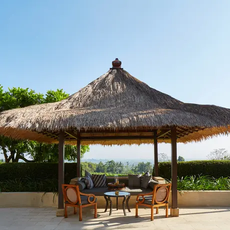 Thatched pavilion with seating area overlooking valley landscape at Amanjiwo.