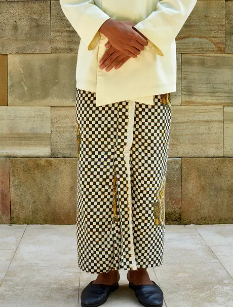 Person wearing cream linen shirt and cream and brown checkerboard trousers at Amanjiwo.
