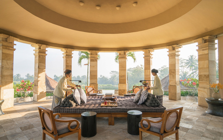 Circular pavilion at Amanjiwo with curved windows framing mountain views, wooden furniture, and natural stone flooring.
