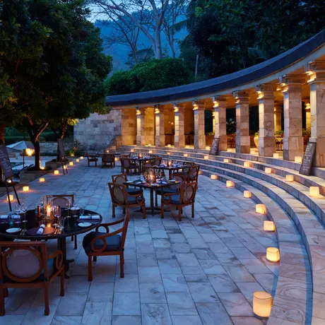Amanjiwo's illuminated terrace at dusk with dining seating overlooking the grounds.